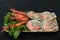 Natural raw scallop with boiled shrimp in the sink with a lettuce leaf in a wooden bowl on a dark background