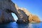 Natural rock arch extending out in the blue sea on the Ionian coast of Greece