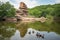 natural rock formation towering over tranquil pond, with ducks swimming in the water