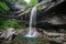 natural rock formation with waterfall cascading from its peak