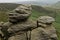 A natural rocks formation with a view of the green fields of the distant landscape in the Peak District National Park Derbyshire