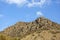 Natural rocky hill in daylight, plants and clear blue sky in the background