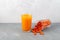 Natural sea buckthorn juice and frozen sea buckthorn berries spilled out of glass on the table. Healthy organic foods to support