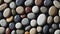 Natural stone background. Multicolored polished pebbles are tightly randomly stacked on a black background.