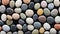 Natural stone background. Multicolored polished pebbles are tightly randomly stacked on a black background.