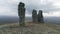 Natural stone sculptures on a hill top on cloudy sky background. Clip. A man looking very small near giant stone pillars