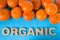 Natural tangerines lie in piles on each other on a blue background with an organic inscription from three-dimensional letters. The