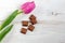 A natural tulip purple, pink and pieces of chocolate on a white wooden background