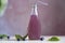 Natural vegan cocktail in bottle with blueberries, seeds, basil extract, leaves. Soft refreshing Asian drink. Blurred