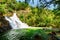 Natural waterfall and scenic emerald pool among green woods