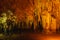 natural white stalagmite or stalactite with orange led light in dark cave in mountain