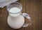 Natural whole milk in glass jug on rustic wooden table