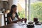 Natural woman with smart-phone sitting on wooden kitchen table