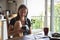 Natural woman with smart-phone sitting on wooden kitchen table