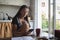 Natural woman with smart-phone sitting on wooden kitchen table