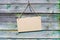 Natural wooden backdrop, brown empty cardboard notice hanging on rope.