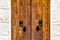 Natural wooden door with black vintage knockers as lion heads and black ornately shaped key-holes