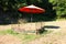 Naturalistic fake straw bed with iron headboard under an orange umbrella in a Tuscan clearing