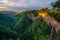 The naturally occurring rocky cliffs are covered with lush greenery on foggy days in morning.