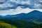 Nature, beautiful cloudy sky, summer landscape in carpathian mountains, wildflowers and meadow, spruces on hills