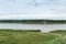 Nature landscape with tributary of Irtysh river and bright blue sky, inflatable boat floating away on water.