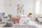 Nature lover`s bright bedroom interior with a wall art of flowers and birds painted on a fabric above a bed which is dressed in g