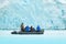 Nature lovers in Arctic Svalbard, Norway. Motor boat with tourists on the ice sea with glacier. Arctic cruise in winter, black pow
