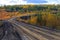 The nature of the Magadan region. Forest road among taiga during golden autumn. Dirt road