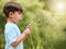 Nature, meadow and child blowing dandelion for wish, hope and growth in field with flowers. Spring, childhood and