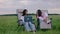 At nature in the middle of field awesome two ladies working on the laptop and enjoy the sunset discussing together while