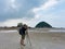 Nature photographer in the action. Alone traveller shoots the seascape with small island background on low tide sandy beach