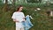 Nature pollution. Young woman, eco activist wearing uniform and rubber gloves with trash bag in hands cleaning forest or
