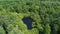 Nature of Russia: dense forest, a small lake, aerial view