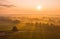 Nature scenery with sun rising above country covered in fog.