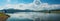 Natures spectacle: panoramic view of a serene dam, majestic mountains, and sky