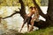 Naughty boy and girl sitting on a branch over water, laughing, having fun talking