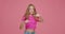 Naughty child girl boxing, punching with fists, kicking at camera. Hooligan schoolgirl fighting on pink studio backdrop