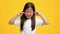 Naughty Little Asian Girl Plugging Ears With Fingers, Yellow Background