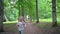 Naughty little girl running through park tree alley in front of camera