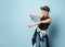 Naughty schoolboy in stylish cap jumping in place looking down under his feet with roguish smile.  isolated on blue background