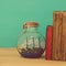 Nautical concept image with sail boat in the bottle next to old books over wooden table. Selective focus.