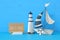 nautical concept image with sail boat, lighthouse and note over blue wooden table and background.