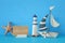 nautical concept image with sail boat, lighthouse, starfish and note over blue wooden table and background.