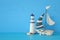 nautical concept with white decorative sail boat, lighthouse, seashells over blue wooden table and background.