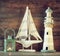 Nautical lifestyle evening concept. old vintage lighthouse, sailing boat and lantern on wooden table. vintage filtered image