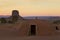 Navajo Hogan at sunrise with a butte in the background