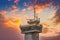 Navigation tower on the sea port against sunrise sky with dramatic clouds