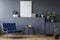 Navy blue armchair next to table in grey flat interior with mockup of poster and plants