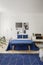 Navy blue bed and radio on cabinet in white bedroom interior with posters and carpet. Real photo