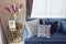 Navy blue modern classic sofa and retro, gray and blue pillows with a lovely orchid vase